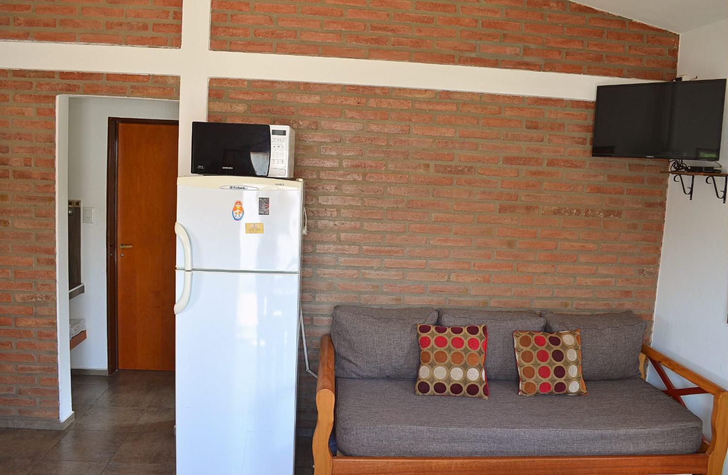 Living con sofá, TV y pared de ladrillo visto